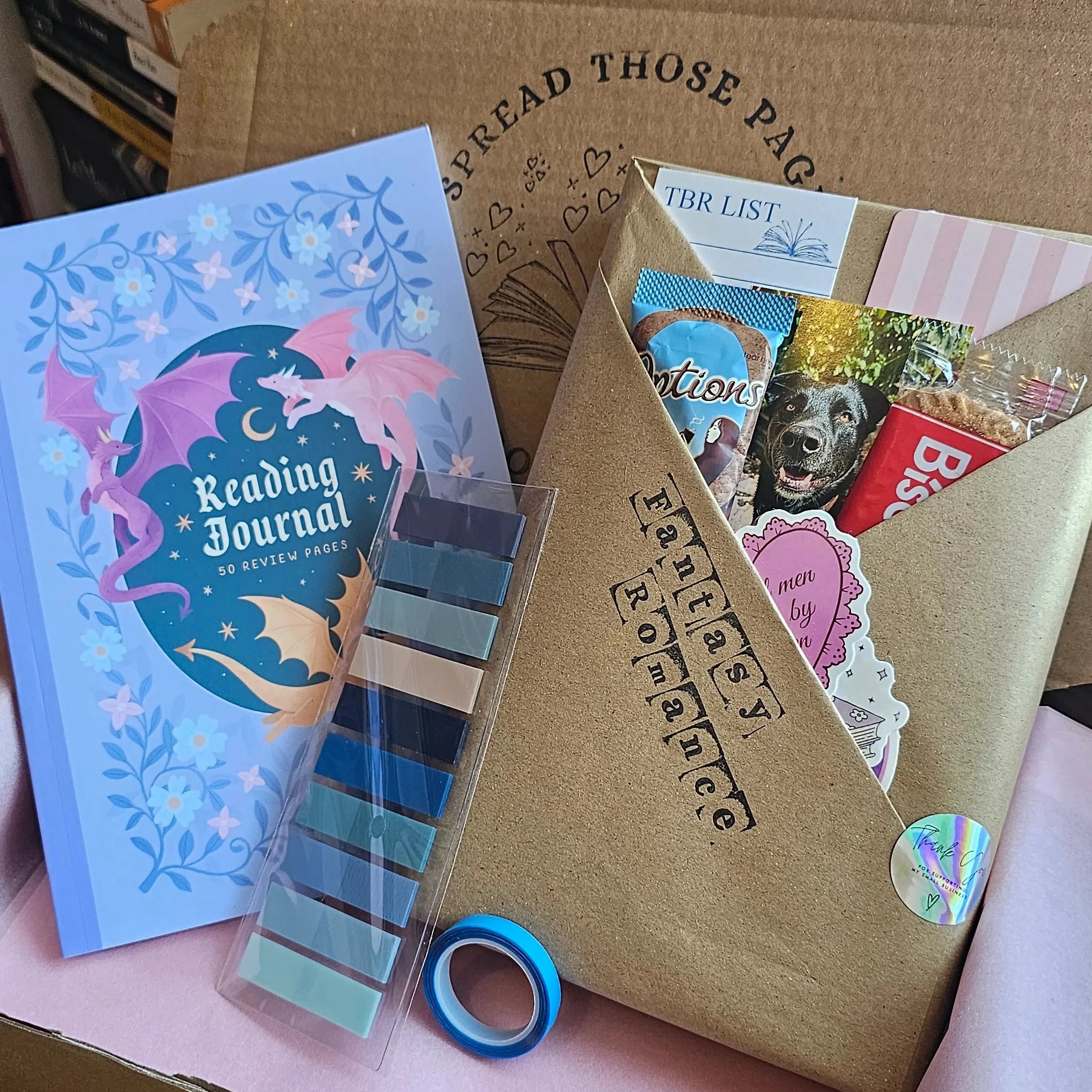 Spread Those Pages Book Reviewer Bundle showing a Fantasy Romance blind date book box, dragon-themed Reading Journal, annotation tabs, and highlighter tape
