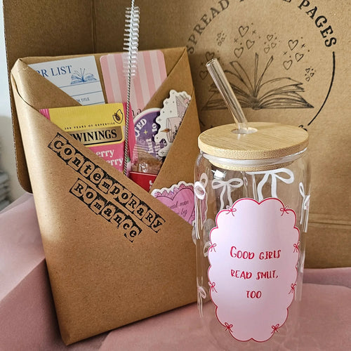 16oz 'Good Girls Read Smut, Too' bookish glass can tumbler with bamboo lid and glass straw, shown next to a Spread Those Pages Contemporary Romance blind date book box with Twinings tea, stickers, and bookish goodies
