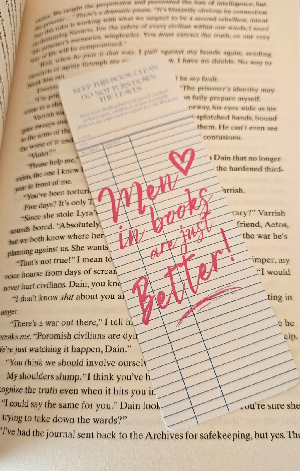 "Library card style romance bookmark reading 'Men in Books Are Just Better' on a romantasy book"