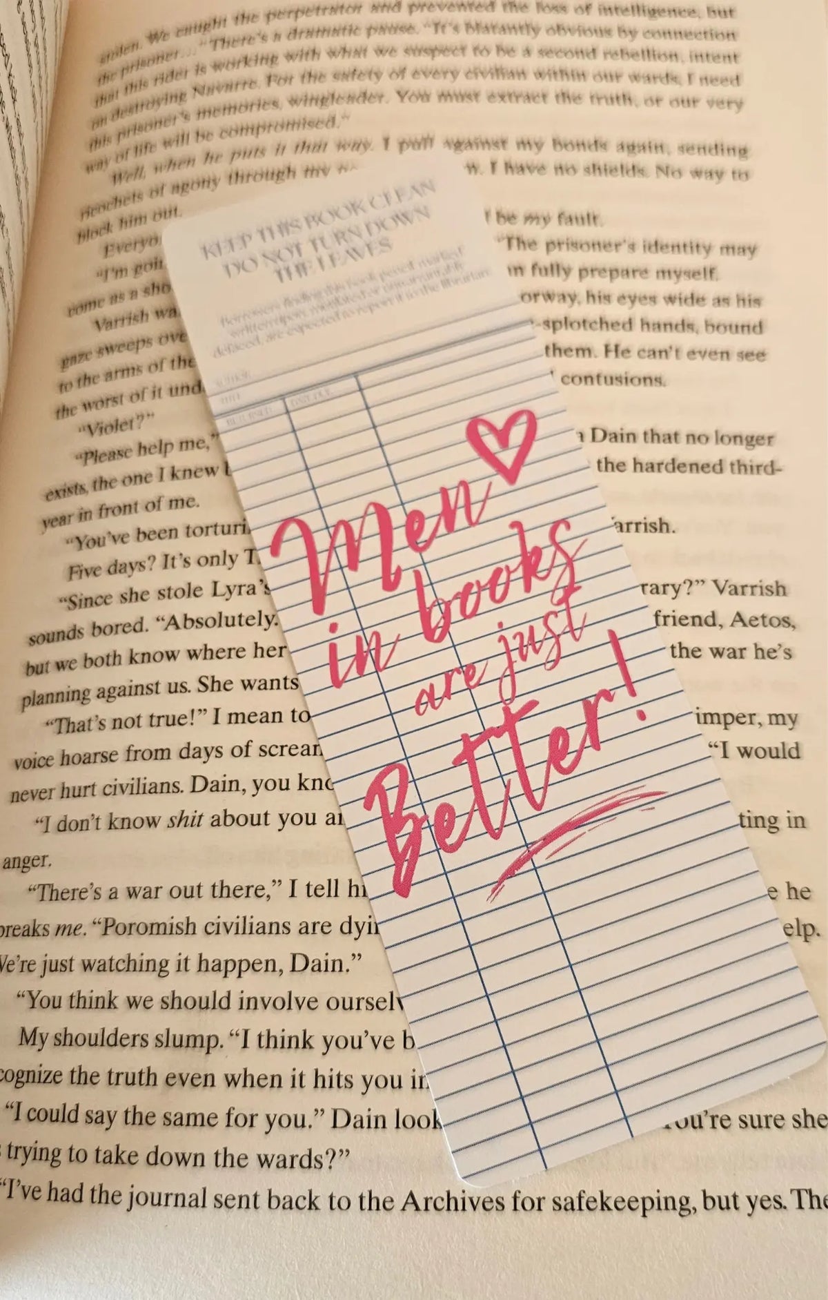 "Library card style romance bookmark reading 'Men in Books Are Just Better' on a romantasy book"