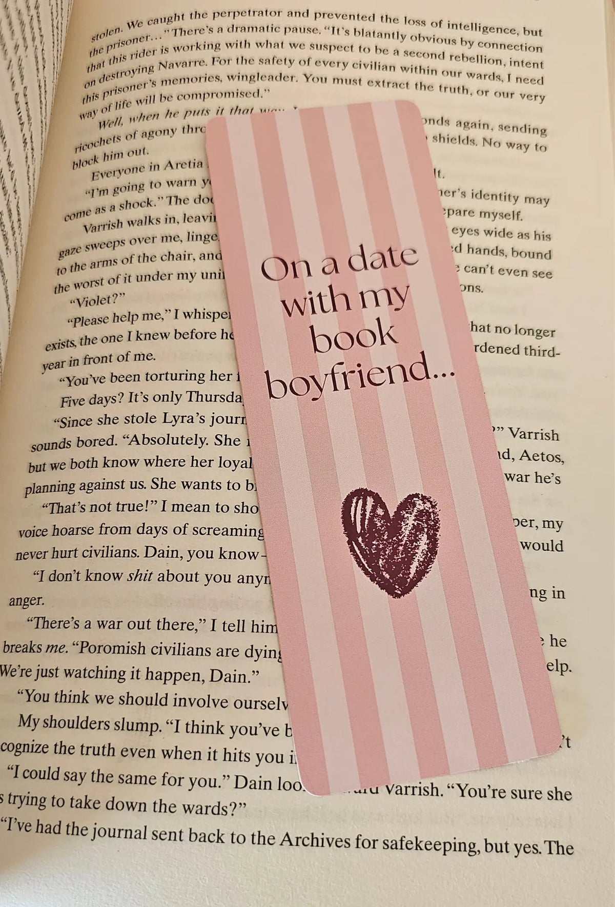 "Pink striped romance bookmark reading 'On a Date with My Book Boyfriend' on a romantasy book"