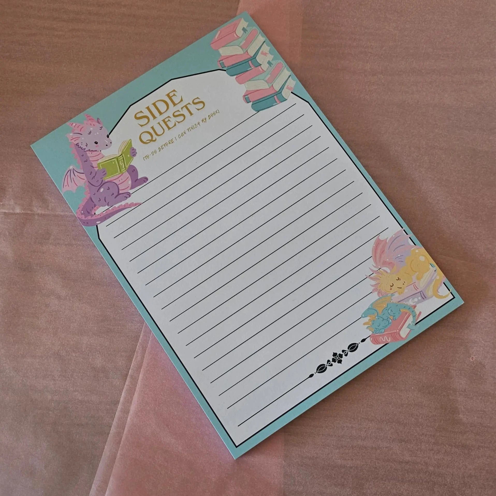 Side Quests fantasy dragon notepad with lined pages, teal border and bookish illustrations on pink background